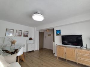 Una sala de estar con un televisor de pantalla plana y una mesa. en Isla de los Pensamientos, en Faro de Cullera