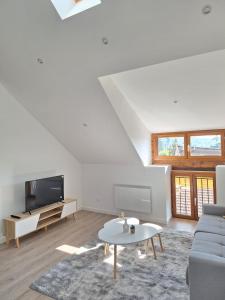 een witte woonkamer met een bank en een tv bij AquaLodge Harmonia in Aix-les-Bains