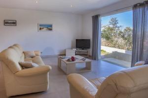 un soggiorno con 2 sedie, TV e divano di Domaine Ghjulia - Casa Nebbiu a Patrimonio Altre 56 foto