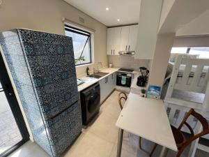 a kitchen with a refrigerator and a table and chairs at Sting-ray Cottage in Port Edward
