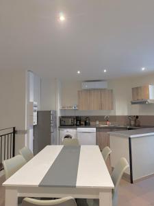 - une cuisine avec une table et des chaises blanches dans l'établissement Le Borie climatisé, à Arles