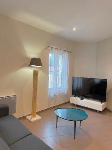 un salon avec un canapé, une table et une télévision dans l'établissement Le Borie climatisé, à Arles