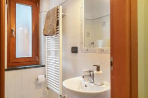 un bagno bianco con lavandino e specchio di La Maisonnette a Valtournenche Altre 27 foto