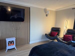 ein Schlafzimmer mit einem Bett und zwei Stühlen und einem Fernseher in der Unterkunft The Guest Room in Aldridge