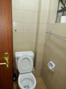 Un baño con inodoro y un rollo de papel higiénico. en Golden Crest, en Nairobi