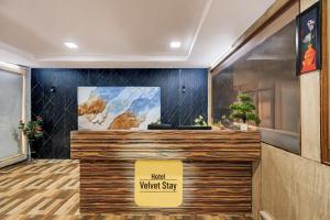 a lobby with a counter with a sign that reads third waited say at Hotel Velvet Stay Near DLF Cyber City in Hyderabad