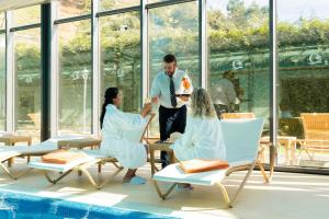 a man and three women sitting in chairs next to a pool at BIO Hotel - Hotel Quinta da Serra in Estreito de Câmara de Lobos +40 photos