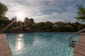 a swimming pool in a yard with the sun shining at Bagode Country Lodge in Desenzano del Garda