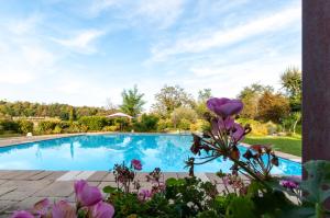 a swimming pool with purple flowers in front of it at Bagode Country Lodge in Desenzano del Garda