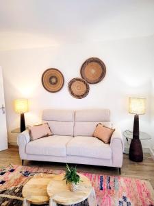 un salon avec un canapé et trois chapeaux au mur dans l'établissement Calme et verdure à Poissy 50 m2 parking terrasse, à Poissy