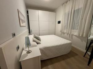 een kleine witte slaapkamer met een bed en een tafel bij Villaggio Michelangelo in Bibione +23 foto's