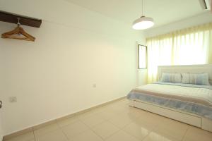 a white bedroom with a bed and a window at Cosy Stay Melaka in Melaka