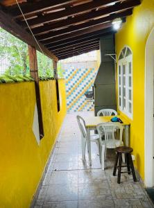 een patio met een tafel en stoelen en een gele muur bij Chalés Boraceia Duda in Boracéia