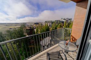 a table and chairs on a balcony with a view at Zlatibor Pine & Peak in Zlatibor