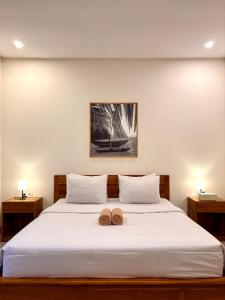 a bedroom with a large white bed with two donuts on it at Kampana Homestay in Uluwatu