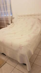 een bed met een witte sprei met roze bloemen erop bij Chambre n 2 in Schiltigheim