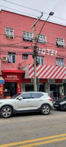 una macchina bianca parcheggiata di fronte a un edificio rosso di Hotel Chalé Centro a Curvelo