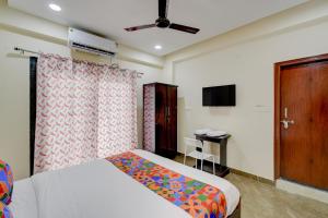 a bedroom with a bed and a table and a television at FabHotel Heaven 75 in Hyderabad
