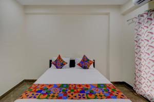 a bedroom with a bed with colorful sheets and pillows at FabHotel Heaven 75 in Hyderabad