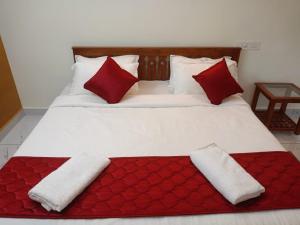 een bed met twee rode en witte kussens erop bij Valley De Hills Farm Villa in Attappādi