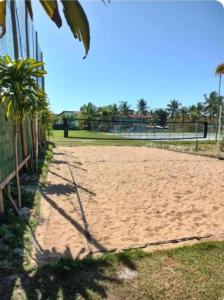 a sandy volleyball court with palm trees and a fence at Portobello in Porto Seguro