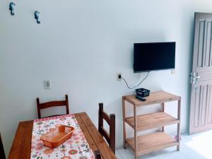 a dining room with a table and a television at Residencial Camirys in Itapoa