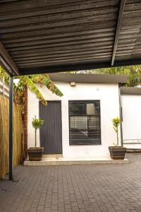 比勒陀利亚Thorne's crip的一座白色房子,庭院里种植了两株盆栽植物