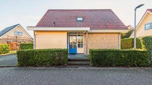 een geel huis met een blauwe deur in een straat bij De Lepelaer in Schoorl