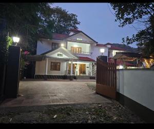 a large white house with a fence in front of it at Greenview homestay in Kalpetta
