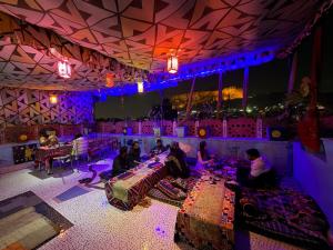 a group of people sitting at tables in a room with purple lighting at Musa's Homestay in Jodhpur +83 photos