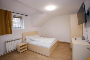 una piccola camera da letto con un letto e una televisione di Casa Andrea a Otopeni