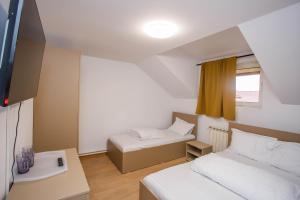 una piccola stanza con due letti e una finestra di Casa Andrea a Otopeni