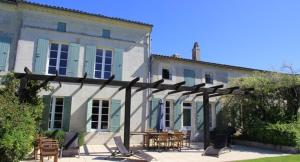 ein großes Gebäude mit einer Terrasse mit Tischen und Stühlen in der Unterkunft Le Font remy in Mortagne-sur-Gironde