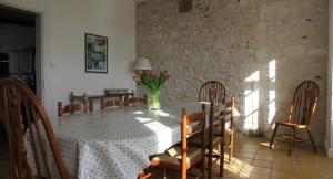 ein Esszimmer mit einem Tisch und einer Blumenvase darauf in der Unterkunft Le Font remy in Mortagne-sur-Gironde