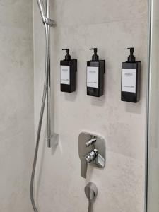 a bathroom with a shower with three soap dispensers on the wall at Stgt Gartenwohnung mit Patio - 4 Personen in Stuttgart
