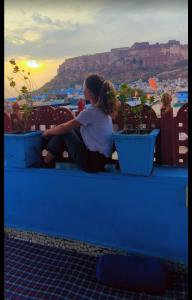 a woman sitting on a blue ledge with plants at Musa's Homestay in Jodhpur