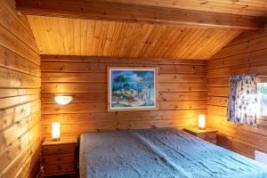 een slaapkamer met een bed in een houten hut bij Mökki Syrjälä in Puumala
