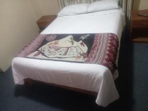 een bed in een hotelkamer met een deken erop bij Pirqainn in Puno