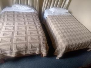 twee bedden naast elkaar in een kamer bij Pirqainn in Puno