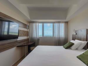 a hotel room with a large bed and a television at Mercure Maceio Pajuçara in Maceió