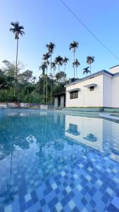 una piscina con un edificio e palme di Grand Glorious Resort a Padinjarathara