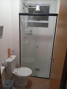 a bathroom with a toilet and a glass shower at Apartamento Serena in Votorantim