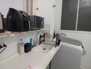 a kitchen counter with a sink and a microwave at Apartamento Serena in Votorantim +2 photos