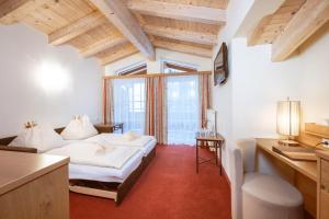 ein Schlafzimmer mit einem Bett und einem Schreibtisch in einem Zimmer in der Unterkunft Hotel Bachschmied in Maria Alm am Steinernen Meer