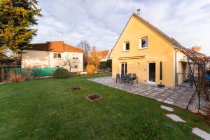 een achtertuin met een geel huis en een gazon bij Le clos Serenity - Jardin & parking in Horbourg