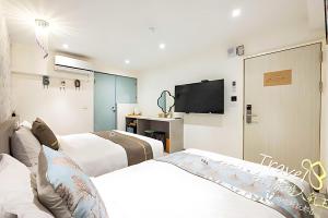 a hotel room with two beds and a flat screen tv at 墾丁卿卿文旅 in Hengchun South Gate