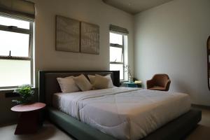 a bedroom with a bed and a chair and two windows at Hotel Aarka in Mettuppālaiyam