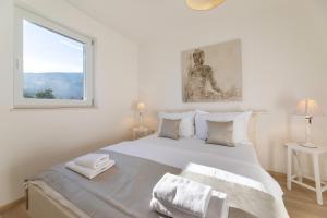 ein weißes Schlafzimmer mit einem großen Bett und einem Fenster in der Unterkunft Pansion Burin in Baška