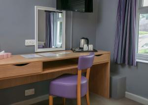een bureau met een spiegel en een paarse stoel bij Tor Park Hotel in Torquay