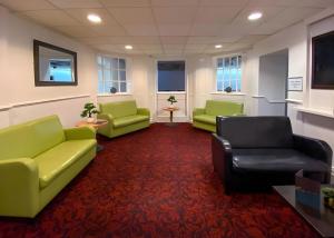 een wachtkamer met groene banken en een rode loper bij Tor Park Hotel in Torquay +5 foto's